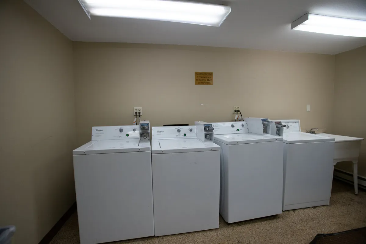 A communal laundry room with washing machines, a drying area, and a utility sink. The space is designed for practicality and community interaction.