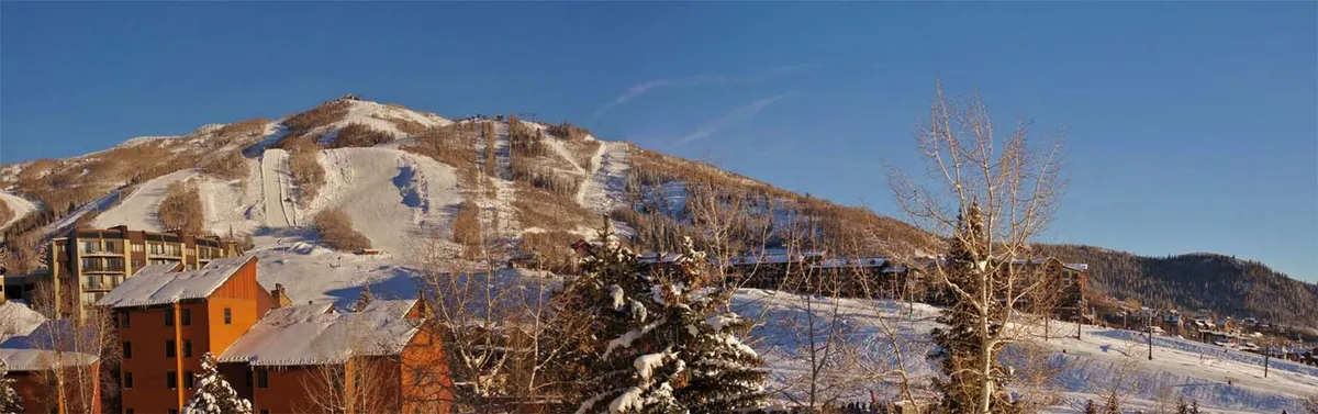 A vibrant exterior scene featuring snow-covered hills, ski slopes, colorful buildings, and bare winter trees. The image conveys an inviting, adventurous mood, highlighting the lively resort community and post-ski relaxation opportunities.